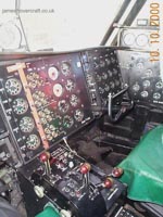 Here a view of the control cabin as seen from the pilot's seat, you can see the control column - with four degrees of motion: left & right controlling pylon movement (+/- 30&deg; from normal), in and out controlling hoverheight and propeller pitch amount interchangeably. <br><br>Also seen are eight red/brown levers. These control, from left to right: Propeller pitch on each propeller: Positive, Zero and Negative; Engine throttle from idle to full power. A selection switch also exists to control whether all four pylons would move synchronously, or whether just the rear two pylons would swivel. <br><br>At the bottom of the two foot wells are the rudder pedals, controlling the angles of the two rear fins to the airflow. <br><br>The pilot and first officer's control column and rudder pedals are mechanically linked to each other, guaranteeing synchronous operation at all times. <br><br>More detail on each of these controls is on the Cockpit Tour page.